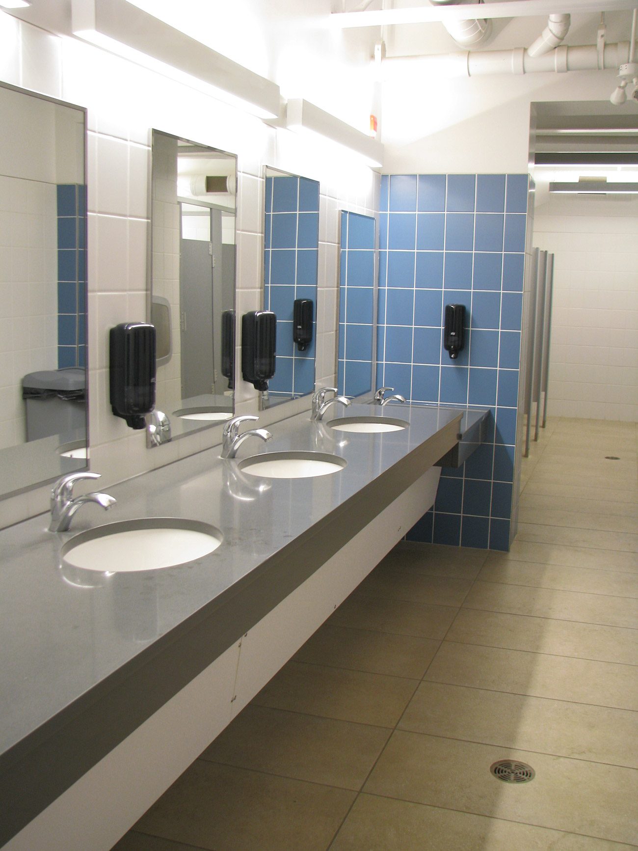Commercial washroom with stainless sinks and tiled walls